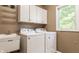 Functional laundry room with modern washer and dryer, overhead cabinets, and a utility sink at 269 Manchester Ct, Noblesville, IN 46060