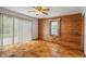 Bedroom featuring wood-paneled walls and a ceiling fan, filled with natural light at 327 S Biltmore Ave, Indianapolis, IN 46241