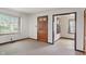 Cozy carpeted living room space with baseboard trim and a wood paneled interior door at 327 S Biltmore Ave, Indianapolis, IN 46241