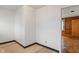 An empty room with wood accents seen through the doorway and worn floors at 327 S Biltmore Ave, Indianapolis, IN 46241