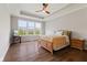 Spacious main bedroom boasts a tray ceiling, wood floors, a ceiling fan, and a large window overlooking the yard at 3678 Sugar Pine Ln, Zionsville, IN 46077