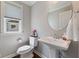 Stylish powder room featuring a pedestal sink, a round mirror, and a window with shade at 3678 Sugar Pine Ln, Zionsville, IN 46077