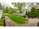 Inviting backyard featuring a brick patio with a fire pit and seating, surrounded by lush greenery and a wooden fence at 440 E 82Nd St, Indianapolis, IN 46240