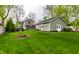 Exterior view of a gray home showcasing the outdoor entertaining space, lush landscaping, and green lawn at 440 E 82Nd St, Indianapolis, IN 46240