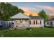 Charming home featuring white siding, red shutters, a cozy front porch, and well-maintained landscaping at sunset at 473 N 17Th St, Noblesville, IN 46060