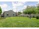 Spacious backyard with lush green grass, trees, and privacy fence on a partly cloudy day at 4902 Kingsley Dr, Indianapolis, IN 46205