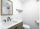 Well-lit bathroom with a modern sink, wooden vanity, white walls, and a minimalist shelf and towel rack at 4902 Kingsley Dr, Indianapolis, IN 46205