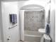 Well-lit bathroom featuring a tub with stylish marble tile surround and updated fixtures at 4927 Mathews Ave, Indianapolis, IN 46227