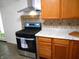 Modern kitchen with black gas range, stainless vent hood, and light wood cabinets at 4927 Mathews Ave, Indianapolis, IN 46227