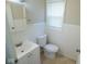 Bright bathroom featuring a white vanity, toilet, and beadboard wainscoting beneath a window at 5080 Norwaldo Ave, Indianapolis, IN 46205