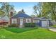 Charming brick home with a well-manicured lawn, lush bushes, and a cozy front porch at 5504 Indianola Ave, Indianapolis, IN 46220