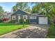 Quaint home featuring a brick facade, green lawn, and a driveway leading to an attached garage at 5504 Indianola Ave, Indianapolis, IN 46220