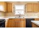 Efficient kitchen featuring wood cabinets, a black dishwasher, and stainless steel sink at 6472 Creekshore Ln, Indianapolis, IN 46268