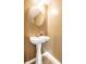 Modern half bathroom with pedestal sink, oval mirror, and wood look flooring at 6472 Creekshore Ln, Indianapolis, IN 46268