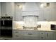 Kitchen detail showcasing gray cabinets, a gas range, and decorative tile backsplash at 7926 White Pine Dr, Avon, IN 46123