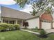 Inviting single-story home with a covered porch, lush landscaping, and a brick-accented two-car garage at 820 Scotch Pine Dr, Greenwood, IN 46143