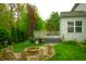 Scenic backyard featuring a fire pit with stump seats surrounded by lush green grass and mature trees and shrubs at 8727 Redditch Dr, Avon, IN 46123