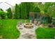 Scenic backyard featuring a fire pit with stump seats surrounded by lush green grass and mature trees and shrubs at 8727 Redditch Dr, Avon, IN 46123