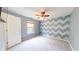 Cozy bedroom features neutral carpet, modern ceiling fan, and an accent wall with light and dark-blue geometric shapes at 8727 Redditch Dr, Avon, IN 46123