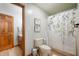Clean bathroom featuring a shower with patterned curtains, a standard toilet, and wood accents at 923 Woodcrest Way, Anderson, IN 46012