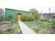 A backyard with a garden, walkway, and green shed with an orange door at 949 Harrison St, Indianapolis, IN 46202