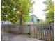View of the home with green siding and a wooden fence in the front yard and mature trees at 949 Harrison St, Indianapolis, IN 46202