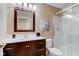 A clean bathroom featuring a dark wood vanity, decorative mirror and a glass-enclosed shower at 9602 Sweet Clover Way, Fishers, IN 46038