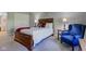 A cozy bedroom featuring a wooden bed frame, plush chair, and soft, neutral carpeting at 9602 Sweet Clover Way, Fishers, IN 46038