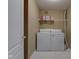 Functional laundry room featuring white appliances, storage shelf, and neutral-toned walls at 9602 Sweet Clover Way, Fishers, IN 46038