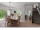 Open dining room with a modern chandelier, adjacent staircase, and backyard view at 9656 Loganberry Ln, Indianapolis, IN 46256