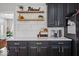 Modern kitchen featuring dark cabinets, gold hardware, and a beverage station with stylish floating shelves at 9656 Loganberry Ln, Indianapolis, IN 46256