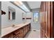 Well-lit bathroom featuring double sinks, wooden cabinets, and a skylight above at 9806 Raintree N Dr, Columbus, IN 47201