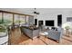 Bright living room featuring modern decor, hardwood floors, large TV, and floor-to-ceiling windows with wooded views at 9806 Raintree N Dr, Columbus, IN 47201