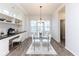 Bright dining room with a glass table, white chairs, and a built-in workstation with cabinets at 13323 Susser Way, Fishers, IN 46037
