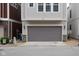 Attached garage with a gray door, stone accents, house number above, and space for parking at 13323 Susser Way, Fishers, IN 46037