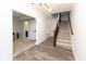 Spacious hallway with wood floors leading to carpeted room and stairs with a dark wood banister at 13323 Susser Way, Fishers, IN 46037