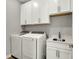 Bright laundry room featuring white cabinets, stainless steel sink, and modern washer and dryer at 15004 Stonneger St, Westfield, IN 46074
