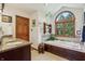 This bathroom features a granite-top sink and jetted tub with an arched window and backyard view at 1508 Redwood Dr, Carmel, IN 46032