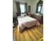 Bedroom with laminate floors, two windows, ornate bed, and matching armoire at 2402 S Rybolt Ave, Indianapolis, IN 46241