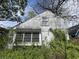 Back of house shows peeling paint, overgrown shrubs, and deteriorating exterior conditions at 2517 Baur Dr, Indianapolis, IN 46220