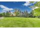 View of an expansive backyard featuring a well-manicured lawn, mature trees, and a stone retaining wall at 2979 Kings Ct, Carmel, IN 46032