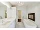Bright bathroom featuring soaking tub, fireplace, white cabinets, and modern fixtures at 2979 Kings Ct, Carmel, IN 46032
