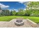 Backyard stone fire pit surrounded by a brick patio with lush greenery and trees in the background at 2979 Kings Ct, Carmel, IN 46032