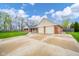 Wide concrete driveway leading to a two-car garage with mature trees surrounding the property at 310 Edgewood E Pl, Anderson, IN 46011