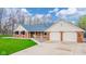 Inviting brick home with covered porch and two-car garage on a manicured lawn at 310 Edgewood E Pl, Anderson, IN 46011