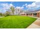 Expansive green front yard with mature trees and a charming brick home in the background at 310 Edgewood E Pl, Anderson, IN 46011