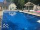 A sparkling in-ground pool with backyard views of the house and pool house at 310 Edgewood E Pl, Anderson, IN 46011