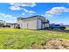 Exterior view of garage featuring grassy yard, gravel parking, and an elevated rear balcony at 3104 Poplar St, Anderson, IN 46012