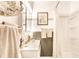 Bright bathroom featuring white cabinetry, decorative mirror, and a tiled shower at 4406 Carrollton Ave, Indianapolis, IN 46205
