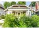 A cozy home with a covered front porch with green bushes obscuring the entrance of the property at 4406 Carrollton Ave, Indianapolis, IN 46205